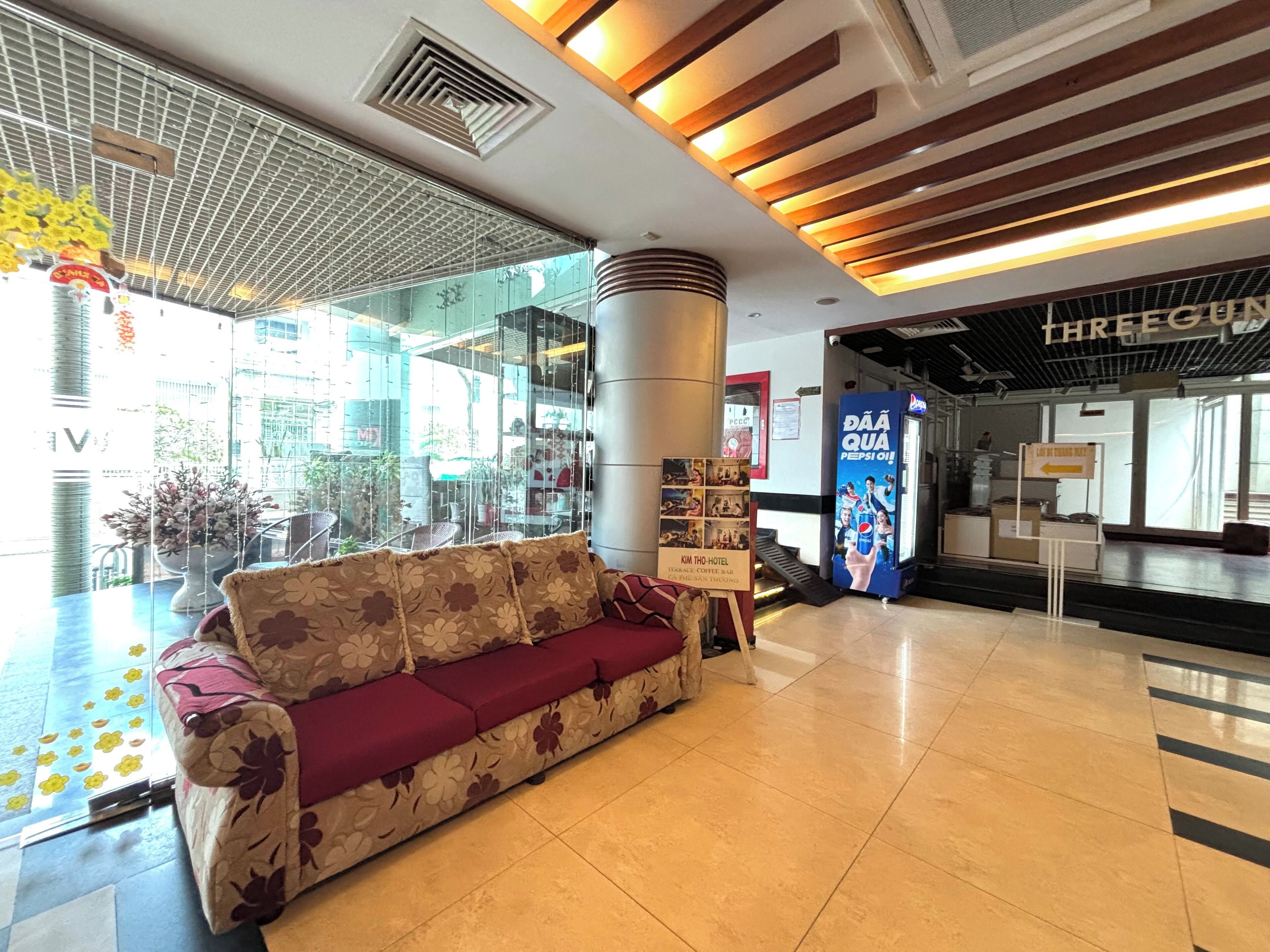 A modern lobby with a sofa, a large pillar, and a Pepsi advertisement.