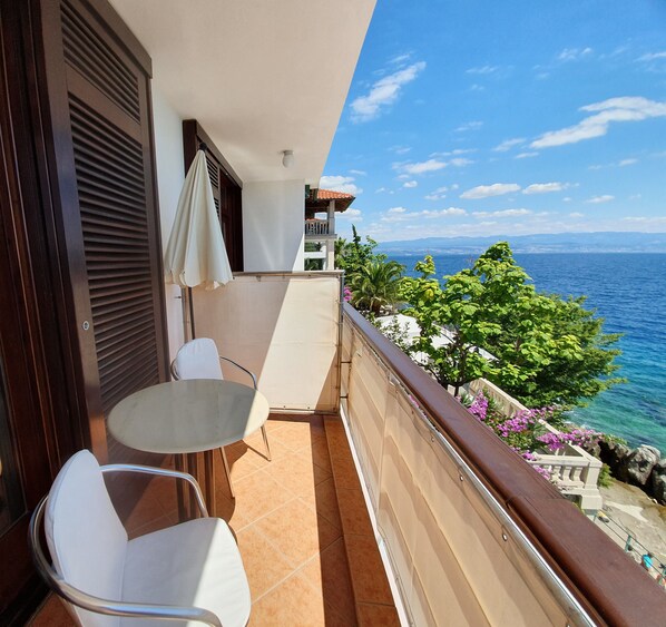 A balcony with a table and chairs, overlooking a coastal view with the sea and distant mountains. - Villa Kleiner (Moscenicka Draga)