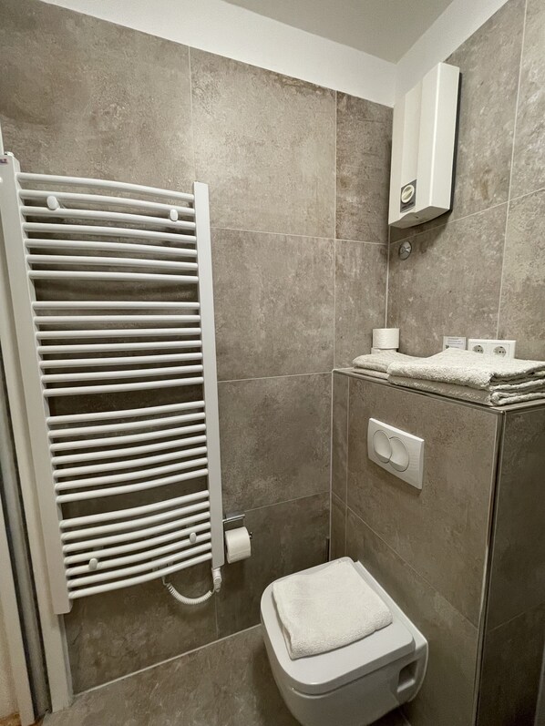 A modern bathroom with a built-in shower, a white toilet, and a towel rack. - Villa Kleiner (Moscenicka Draga)
