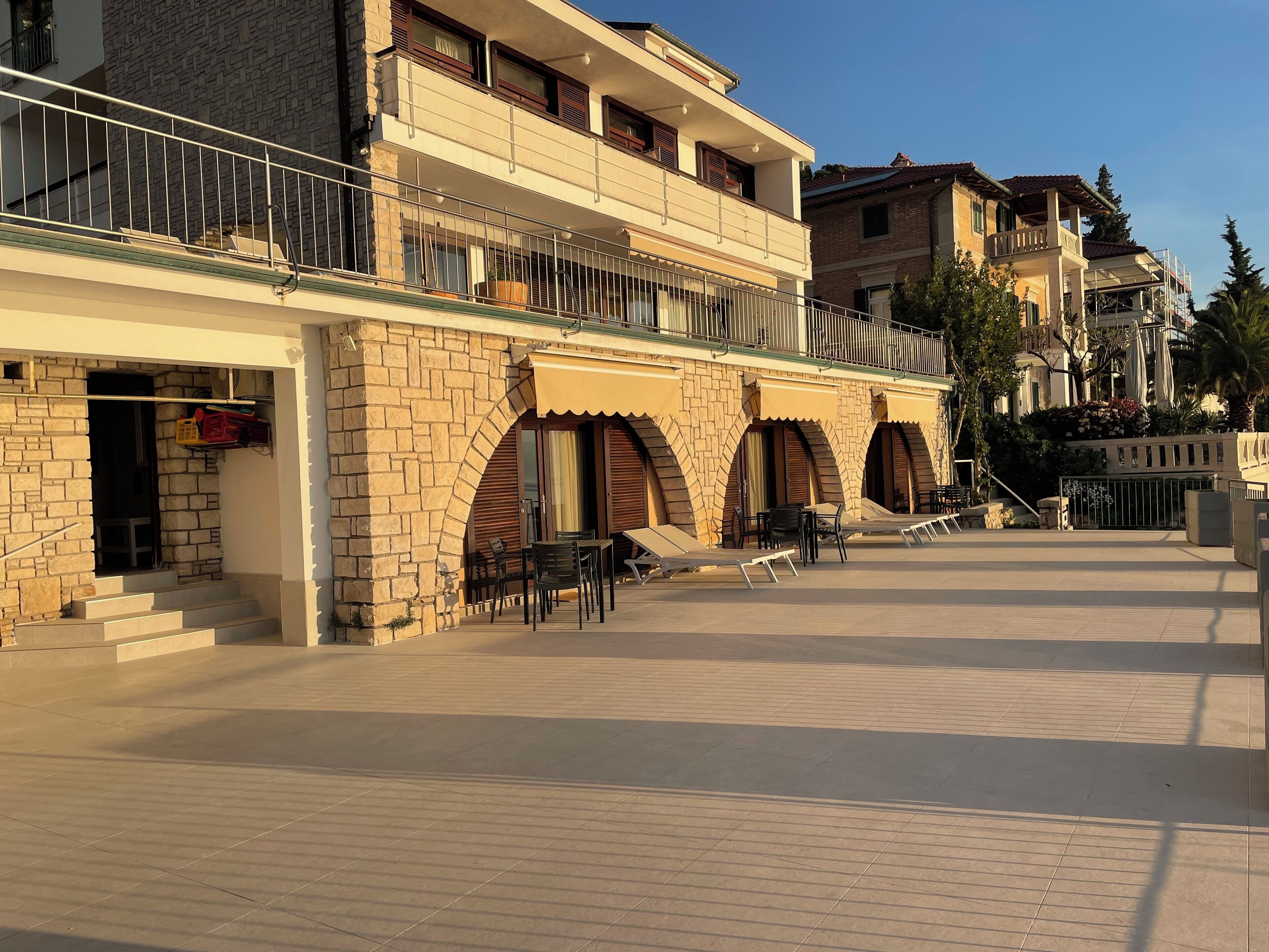 A hotel with a stone facade, outdoor seating area, and a clear sky.