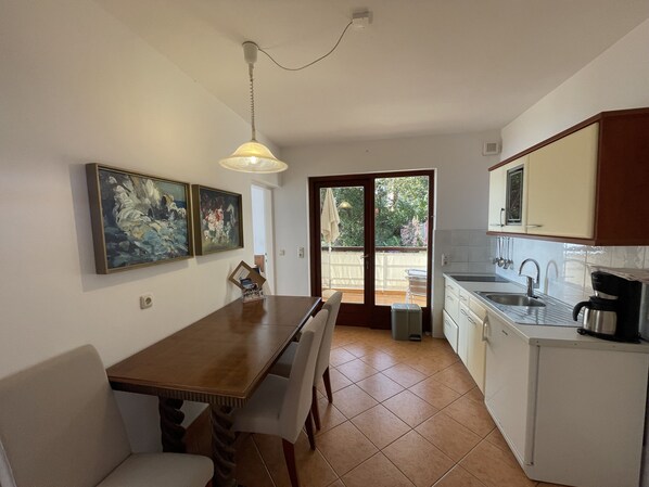 A compact kitchen with a dining table, chairs, a coffee machine, and a view to the outside. - Villa Kleiner (Moscenicka Draga)