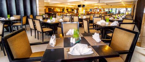 A spacious restaurant with high ceilings, modern lighting, and a clean, organized layout.