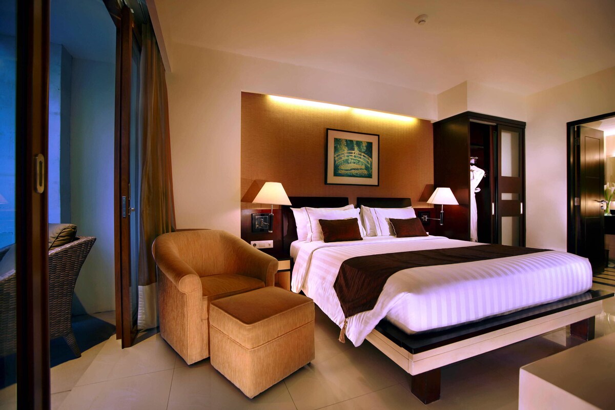 A hotel room with a large bed, a sofa, a desk, and a chair.