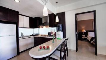 Een moderne keuken met een centraal eiland, donkere kastjes en een eethoek met een tafel en stoelen.