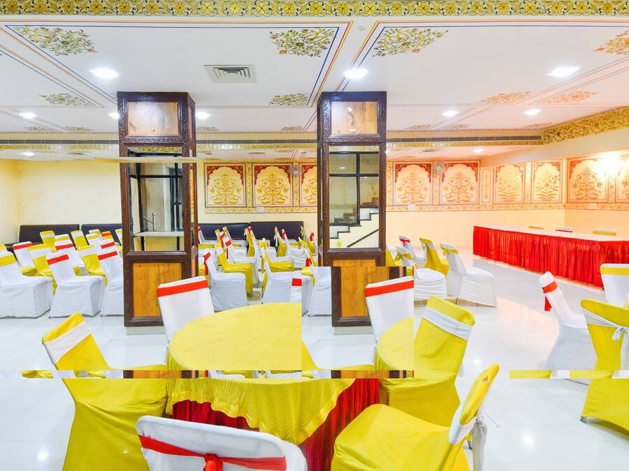 A banquet hall with rows of tables and chairs, ornate ceiling decorations, and a staircase.