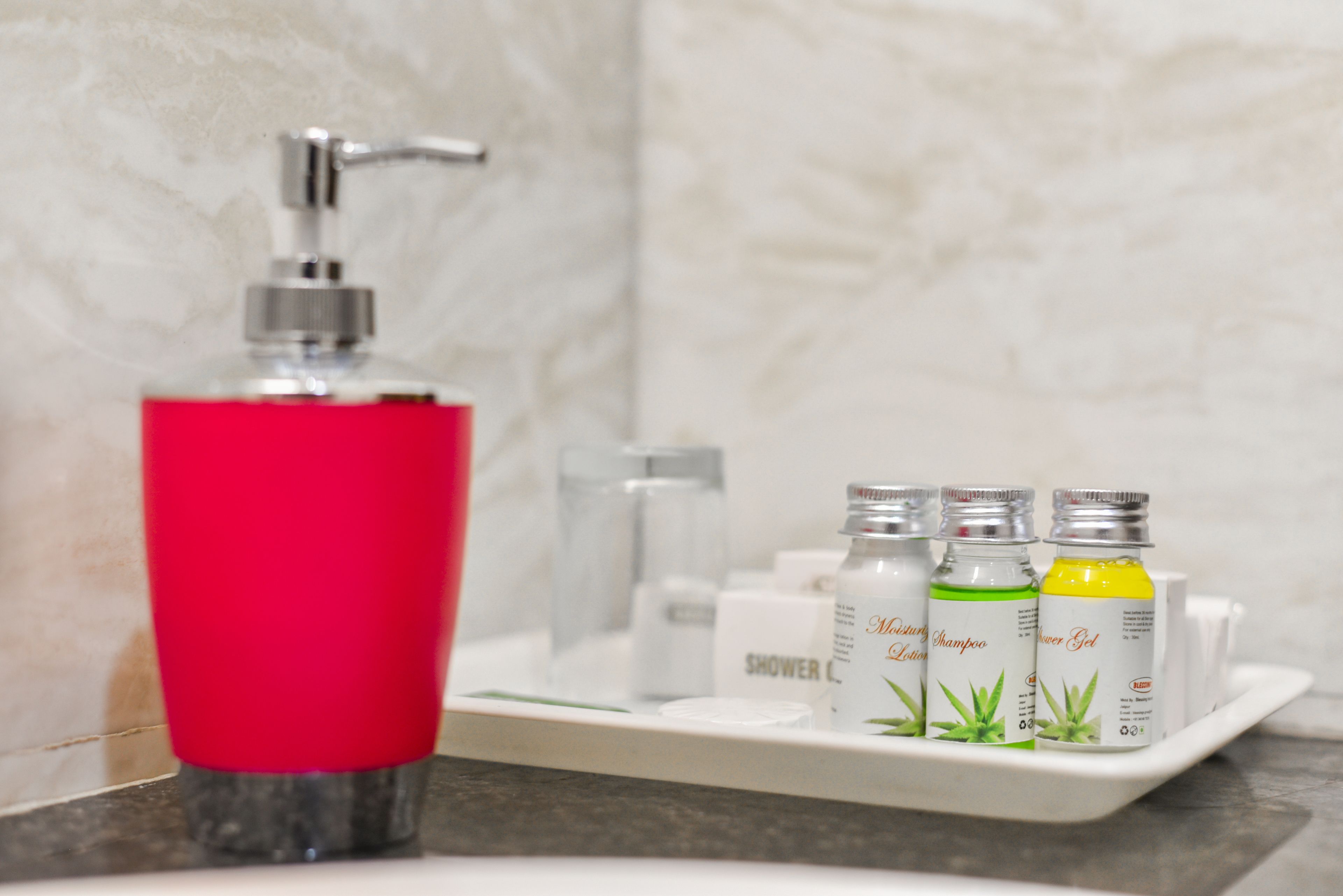 Ein Badezimmer mit rotem Seifenspender, Duschkorb und drei Flaschen Shampoo und Conditioner.