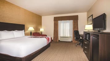 Habitación de hotel con una cama grande, dos lámparas de noche, un escritorio con silla, televisión y minibar.