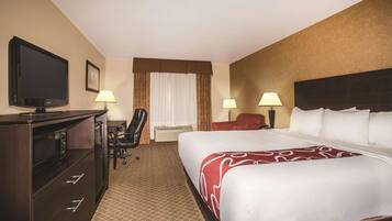 A hotel room with a bed, a desk, a television, and two lamps.