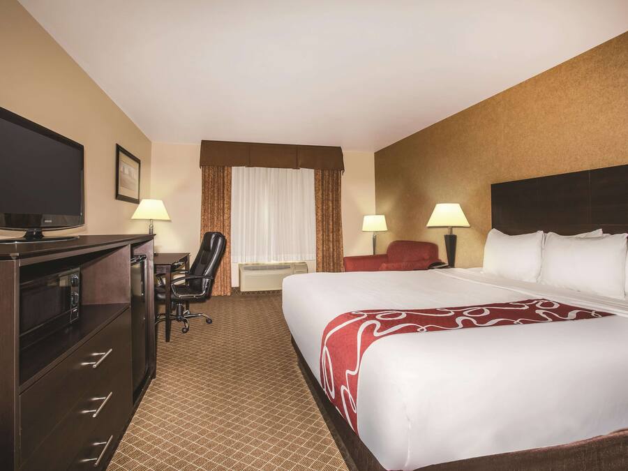 A hotel room with a bed, a desk, a television, and two lamps.
