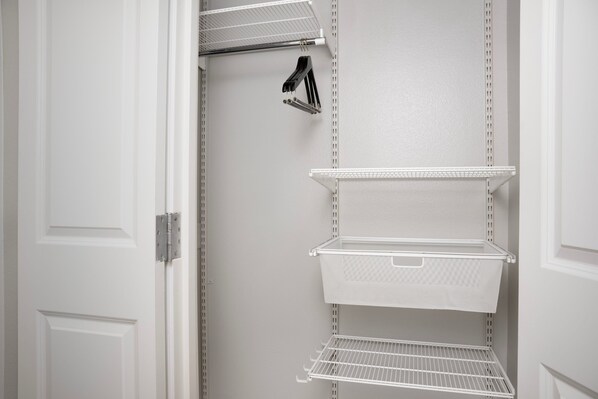 A white closet with three wire shelves and a hanging rack. - TownePlace Suites Dallas DeSoto (DeSoto)