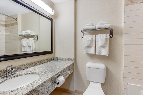 A bathroom with a granite countertop sink, a toilet, and a towel rack with folded towels. - Best Western Wainwright Inn & Suites (Wainwright)