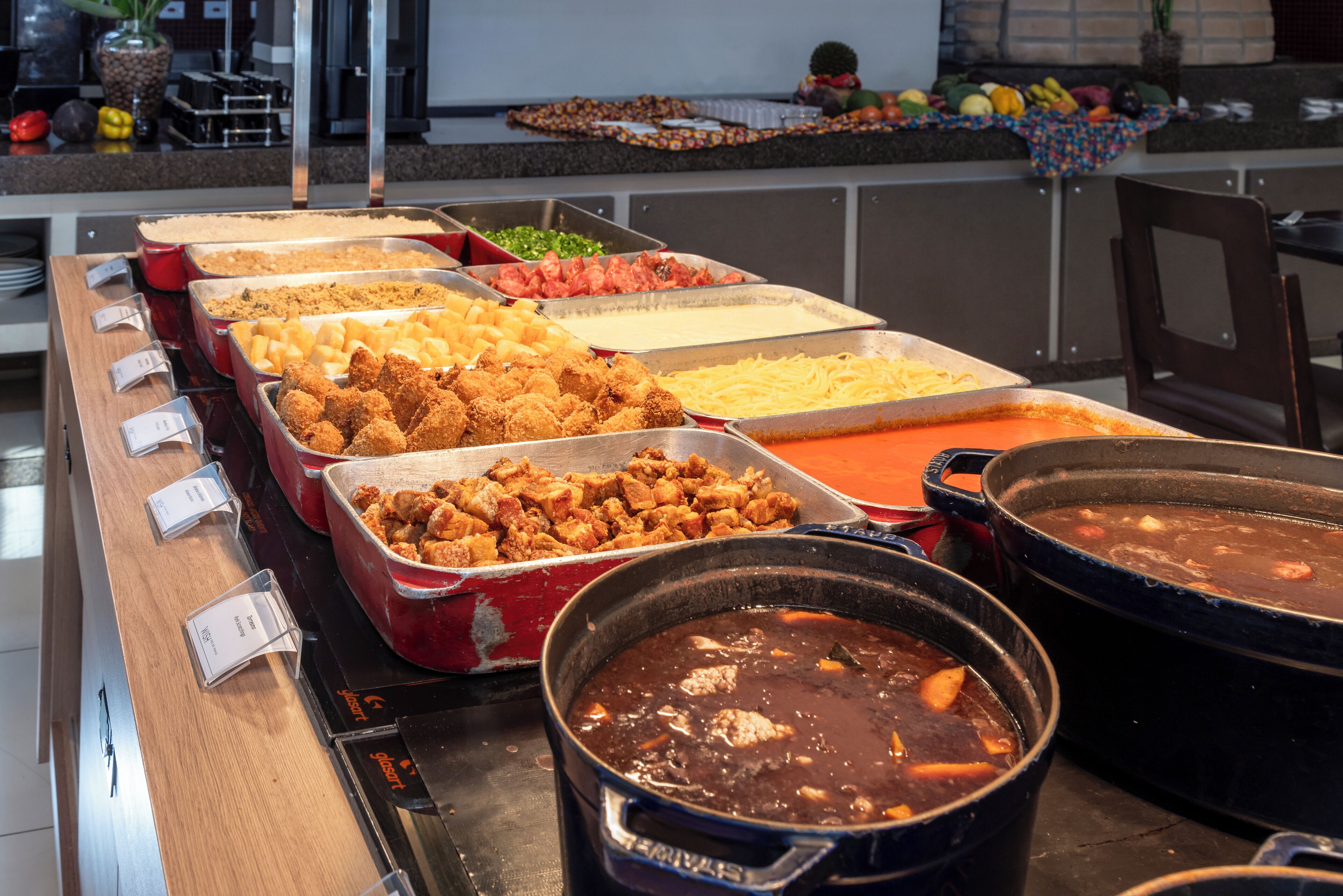 A buffet with various dishes including fried chicken, pasta, and a large pot of stew.