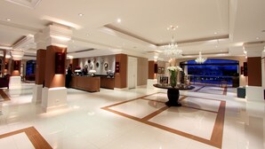 A spacious lobby with a reception desk, a chandelier, and a large window offering a view of the outside. - Wish Foz do Iguaçu (Foz do Iguaçu)
