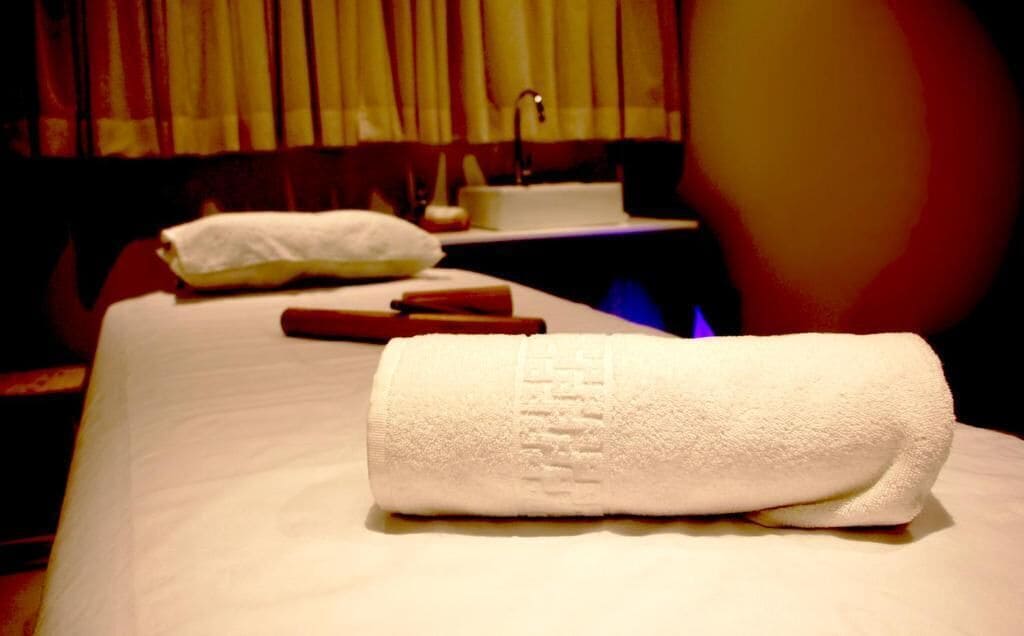 Quarto de hotel com cama bem arrumada, travesseiro e toalha.
