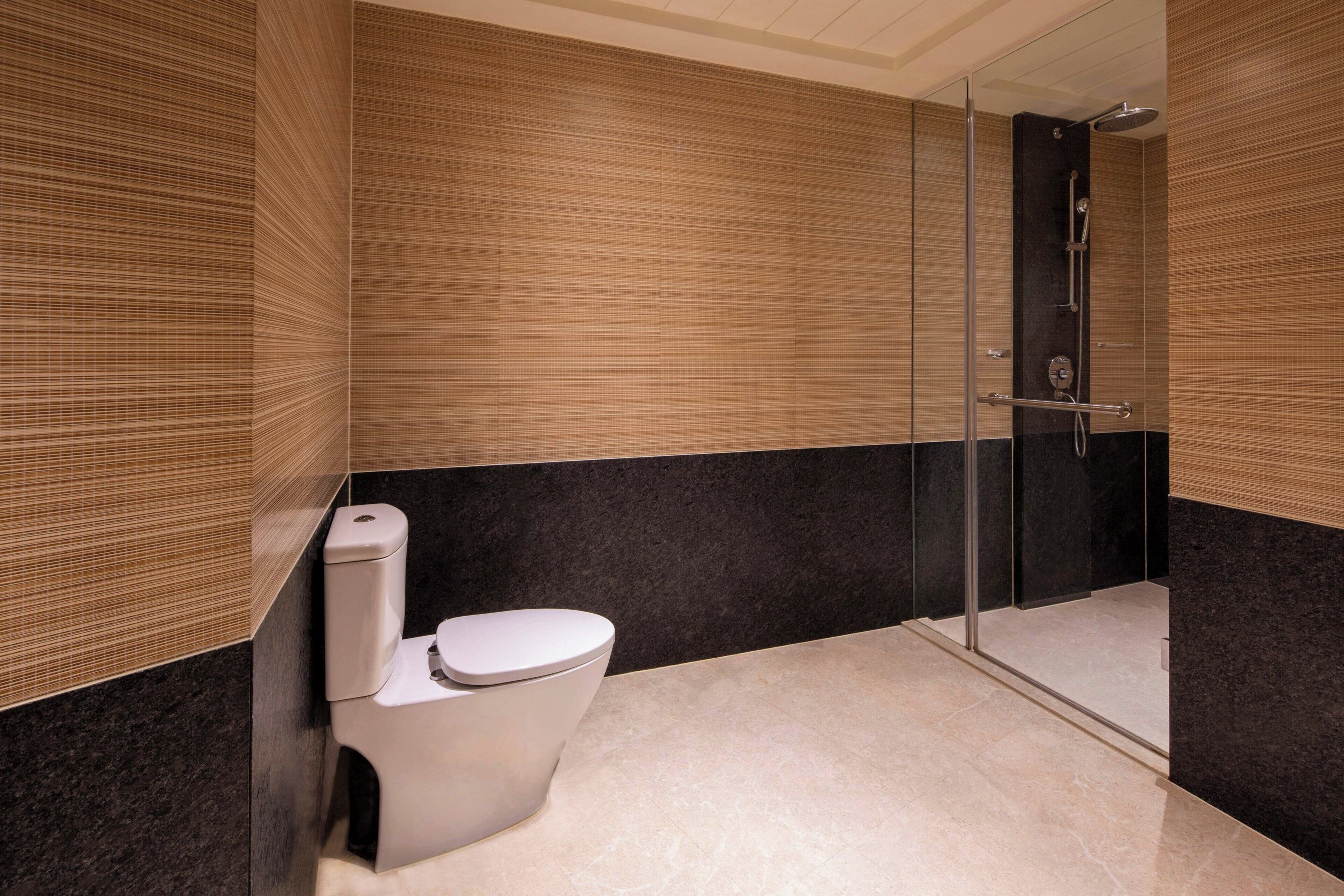 Et moderne badeværelse med toilet, brusebad og et bruseområde med glasvægge.