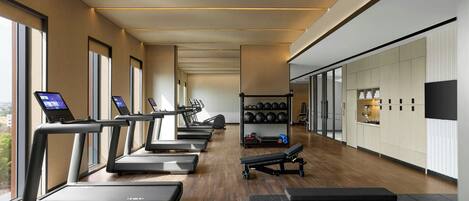 A modern gym with treadmills, a bench, and a weight rack.