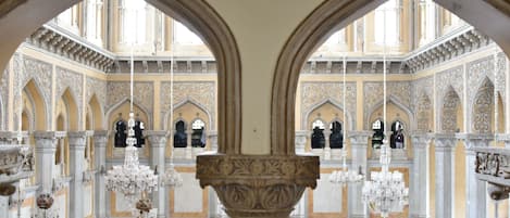An ornate interior with high ceilings, arched windows, and intricate wall designs.