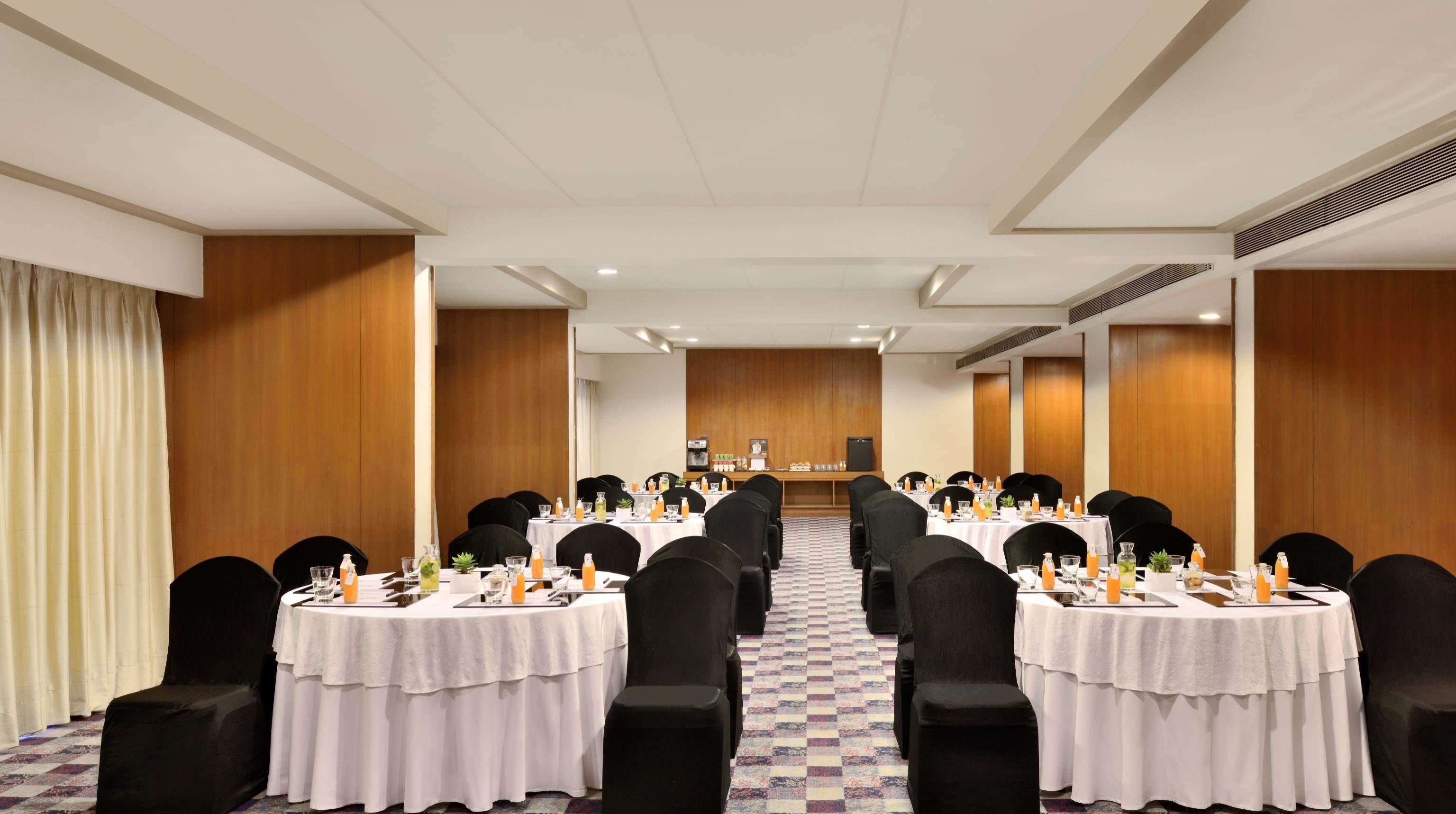 Une salle de conférence équipée de plusieurs tables, de chaises et d’un pupitre.