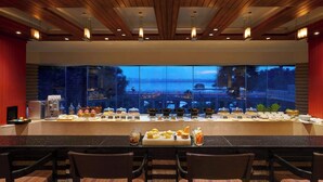 Un buffet proposant une grande variété de plats, avec une vue sur le paysage urbain au crépuscule.