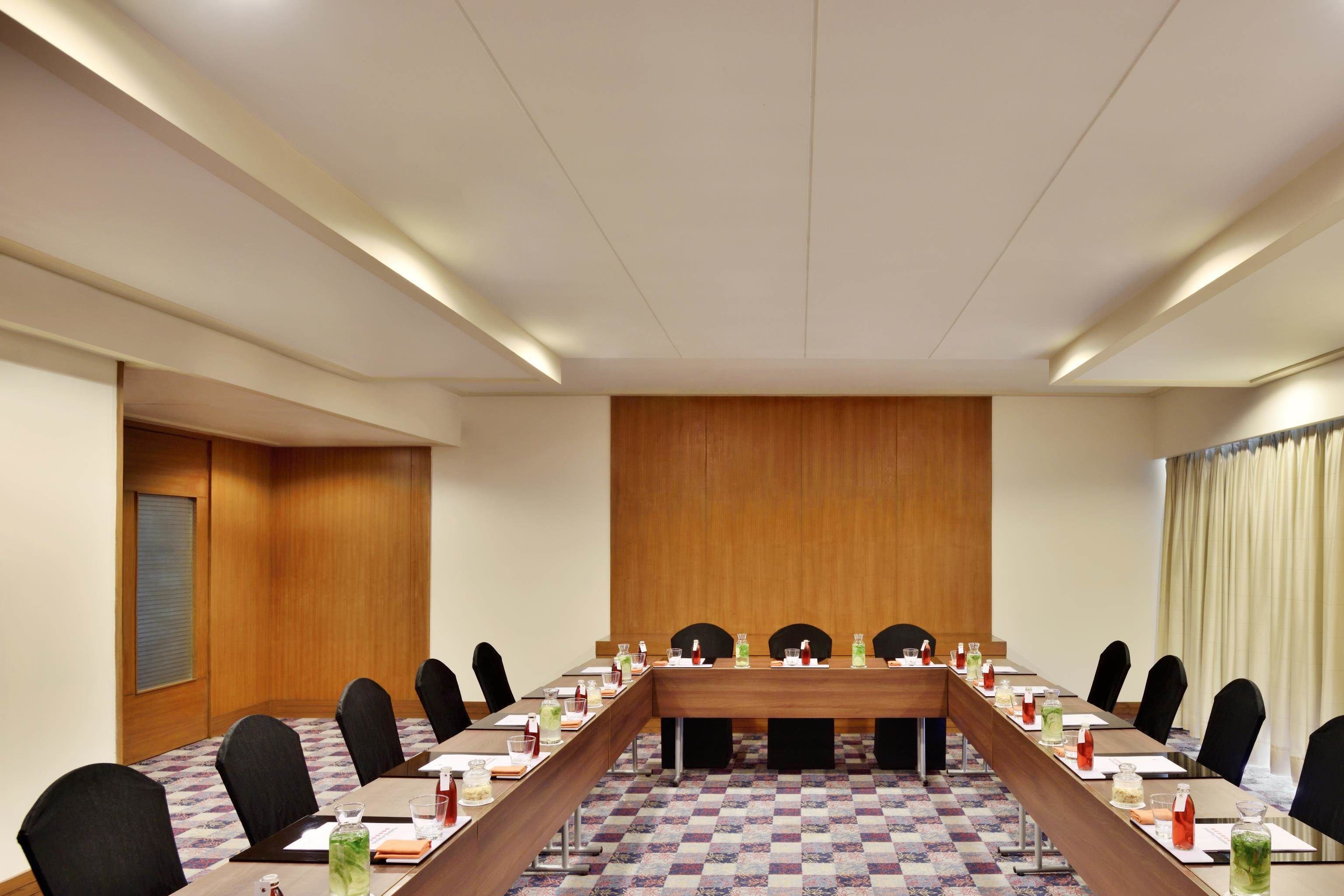Un salón de conferencias con una mesa larga, sillas y suelo a cuadros.