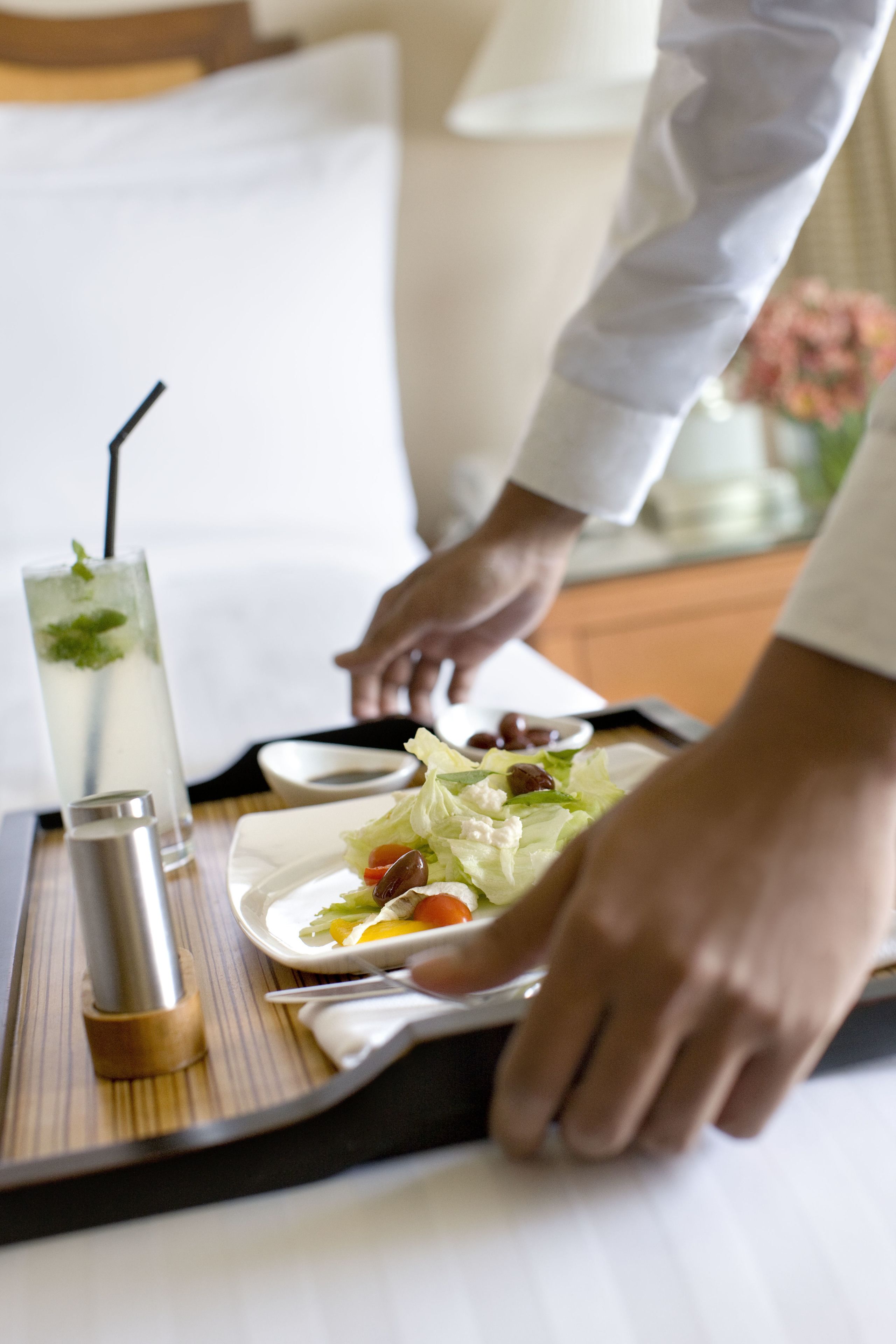 Una bandeja con ensalada, una bebida y un salero sobre una mesa en una habitación de hotel.