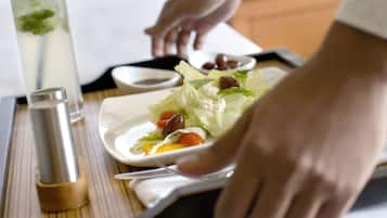 Una bandeja con ensalada, una bebida y un salero sobre una mesa en una habitación de hotel.