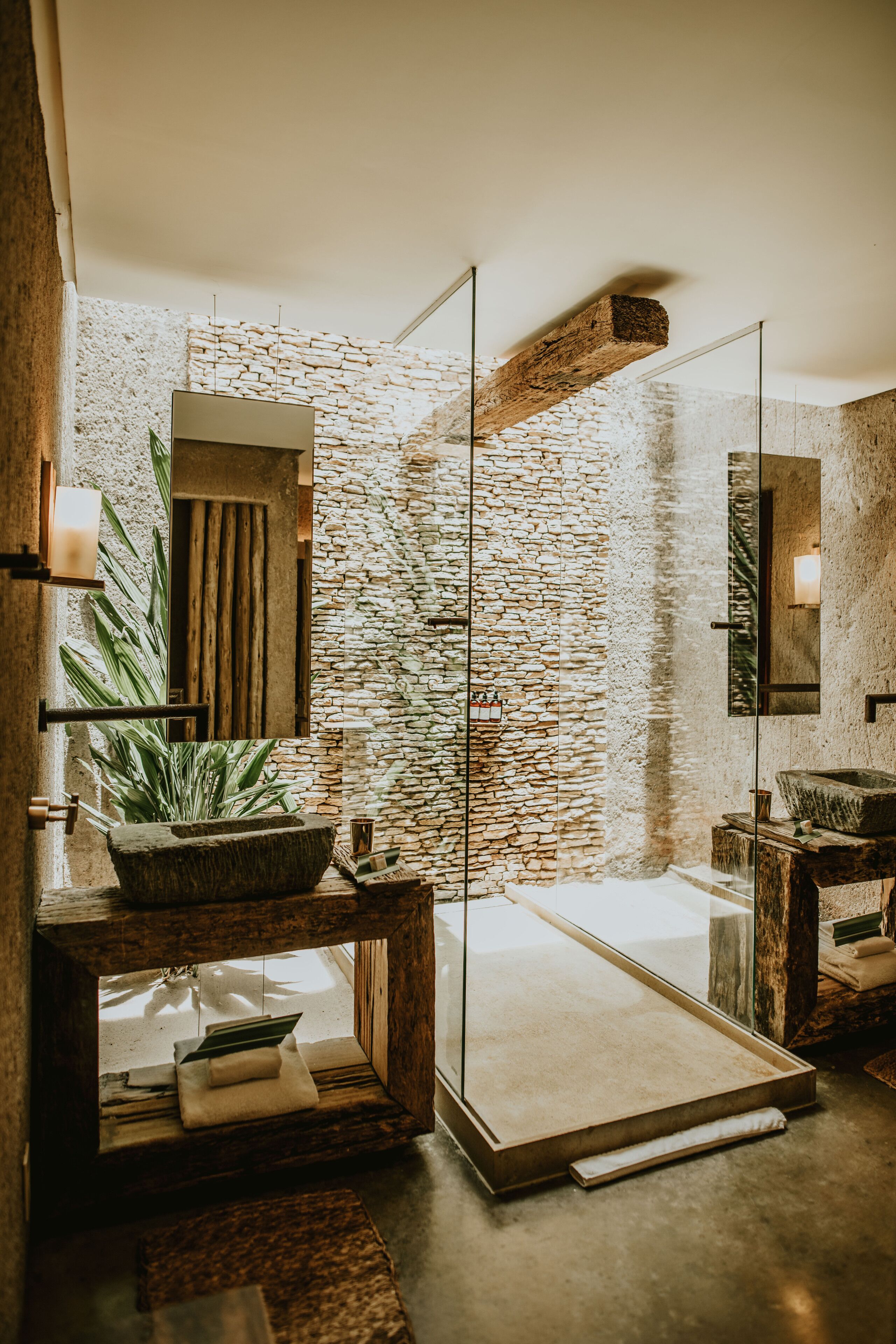 Une salle de bain moderne avec un mur en pierre, une douche en verre et des éléments décoratifs en bois.