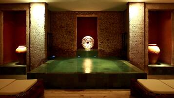 A spa room with a stone wall, a central water feature, and two side lamps.