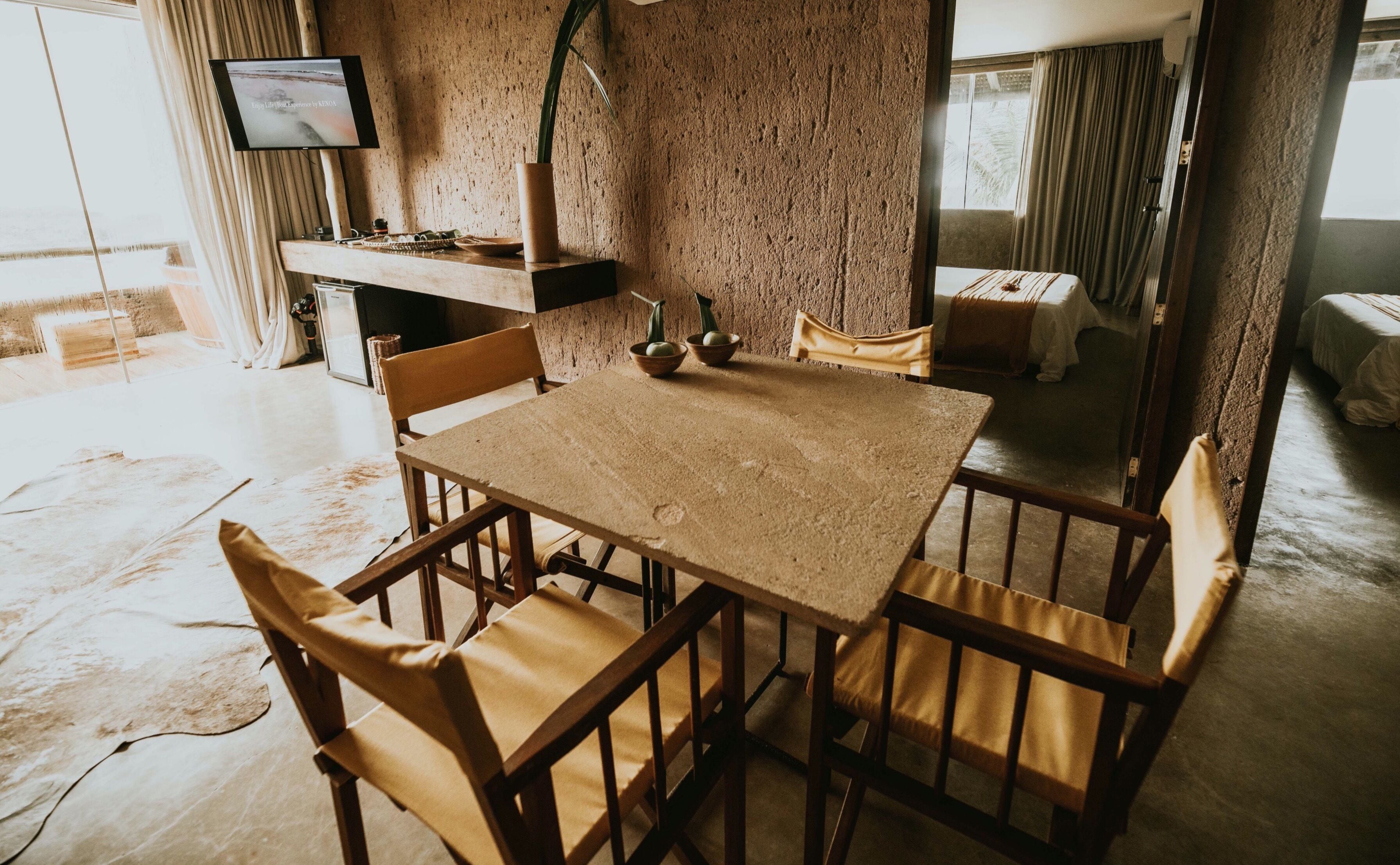 Ein rustikaler Essbereich mit Holztisch und -stühlen, einem Fernseher an der Wand und Blick ins Freie.