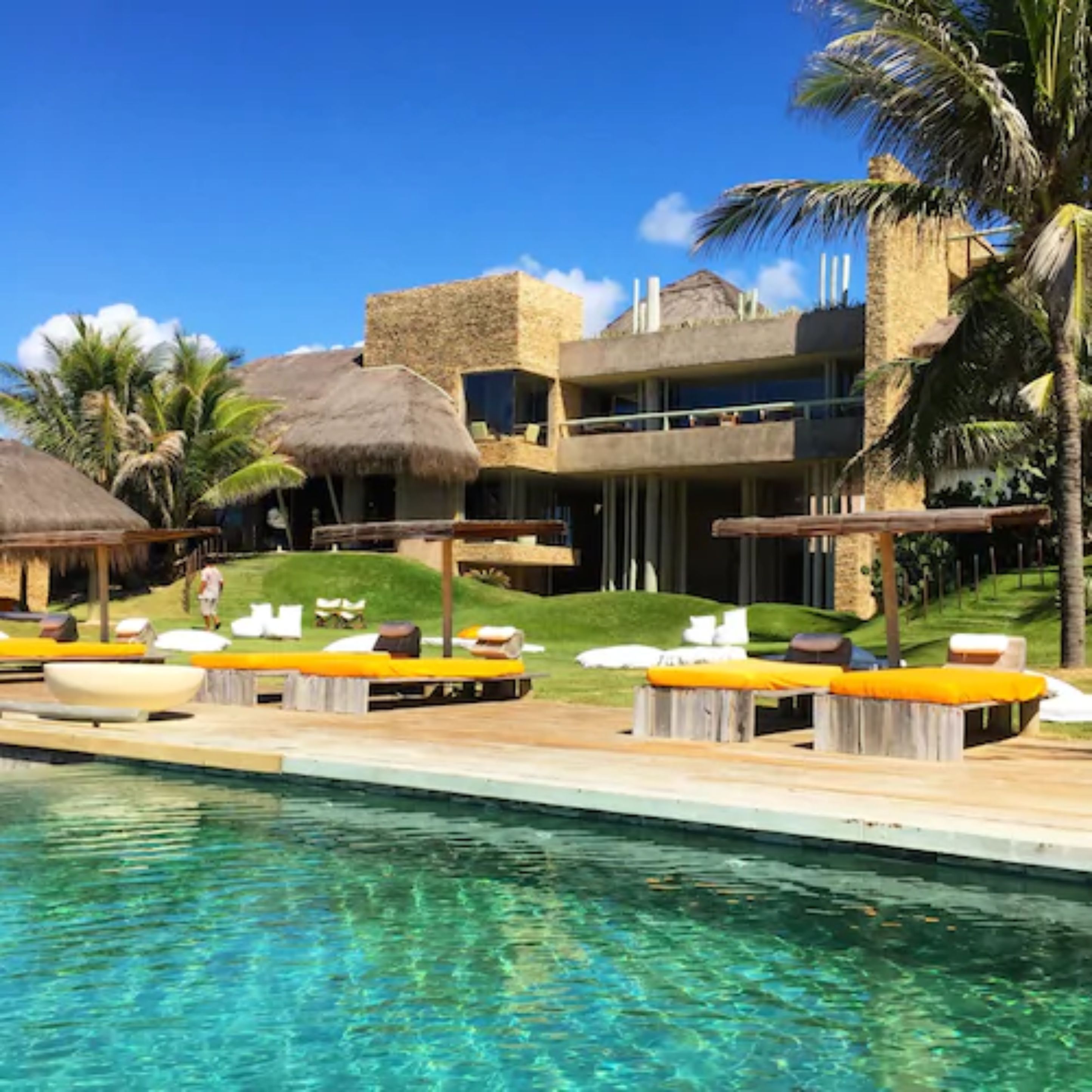 A resort with a pool, thatched-roof huts, and outdoor seating.