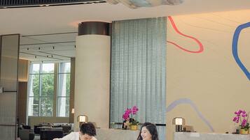 A spacious lobby with a large mural, a reception desk, and a seating area.