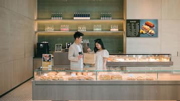 A bakery display with pastries, a menu board, and a counter with a person and a customer.