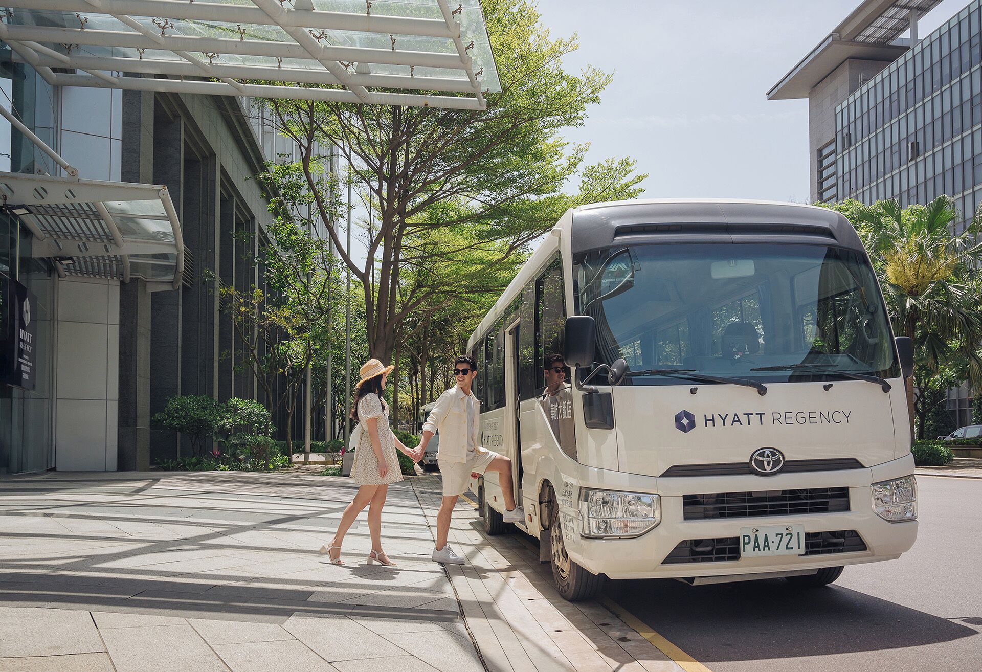 Un autobús blanco con la marca 'HYATT REGENCY' estacionado en una calle de la ciudad.