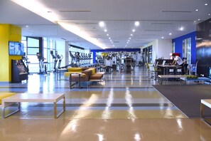 A modern gym with cardio equipment, weight machines, and a seating area with yellow and brown chairs. - Hyatt Regency Taoyuan International Airport (Taoyuan City)