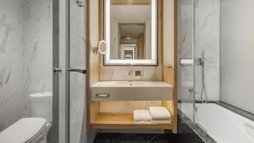 Un baño moderno con tocador de mármol, cabina de ducha de vidrio y un inodoro.