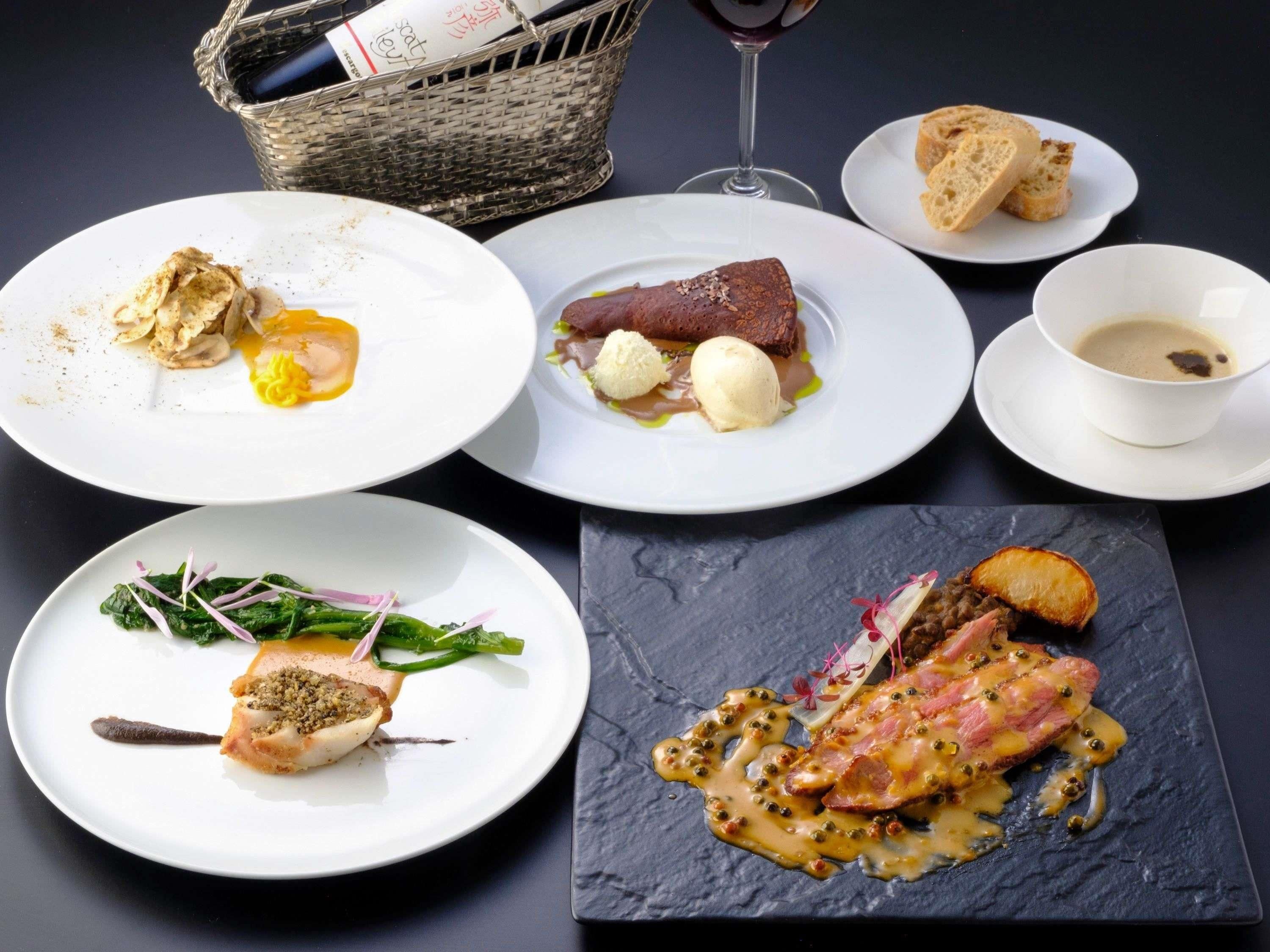 A variety of dishes on plates, a glass of wine, and a basket with a book.