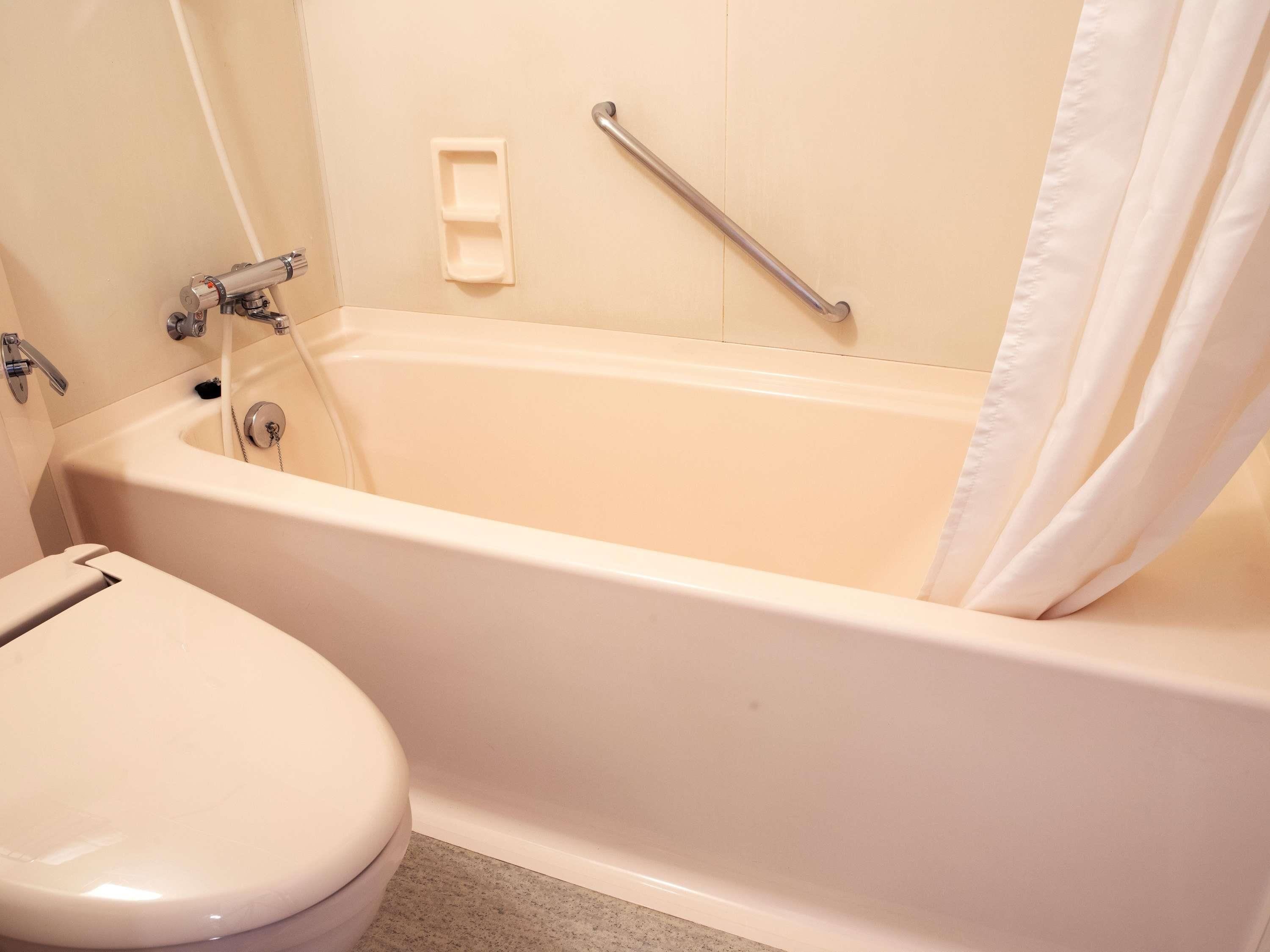 Baño con bañera, inodoro y barra de apoyo.