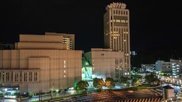 A nighttime cityscape with modern buildings, a prominent tower, and a well-lit intersection.