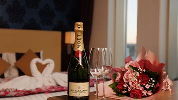 A bottle of Moet & Chandon champagne, two empty wine glasses, and a bouquet of flowers on a wooden table in a hotel room.