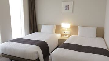 A hotel room with two beds, a bedside table with a lamp, a telephone, and a framed picture on the wall.