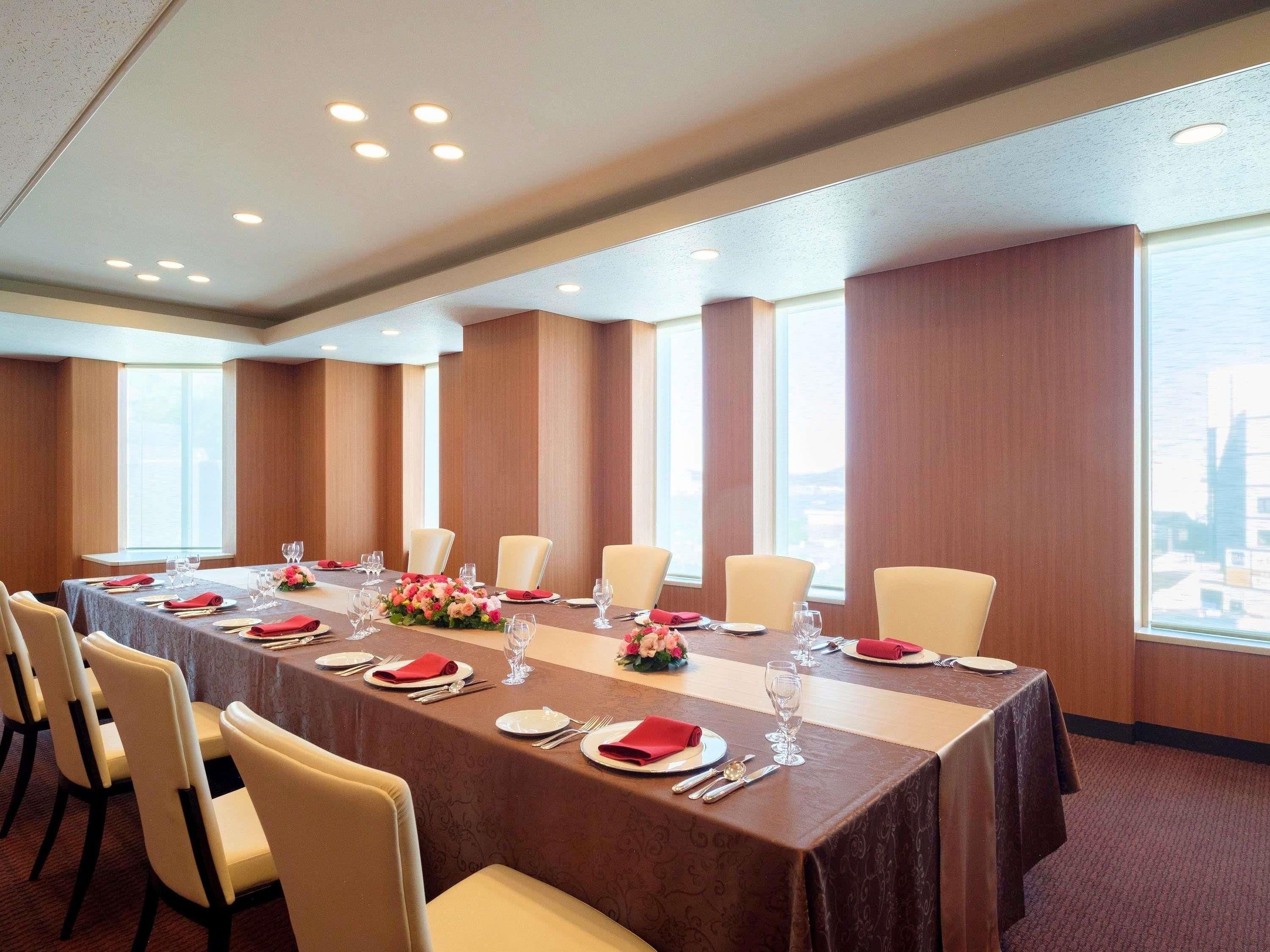 A conference room with a long table, chairs, and large windows.