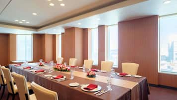 A conference room with a long table, chairs, and large windows.