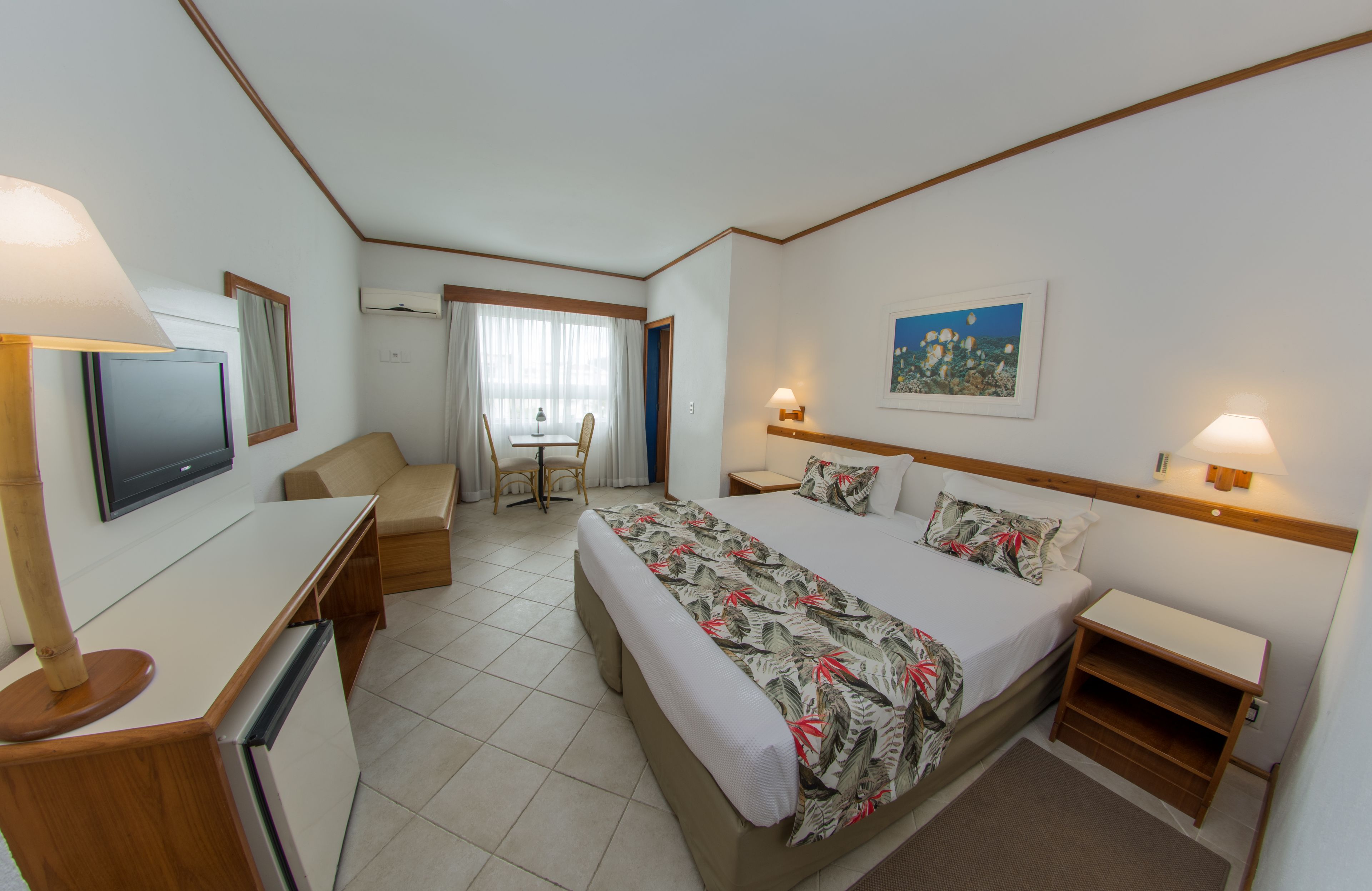 Una habitación de hotel con cama, escritorio, silla y televisor.