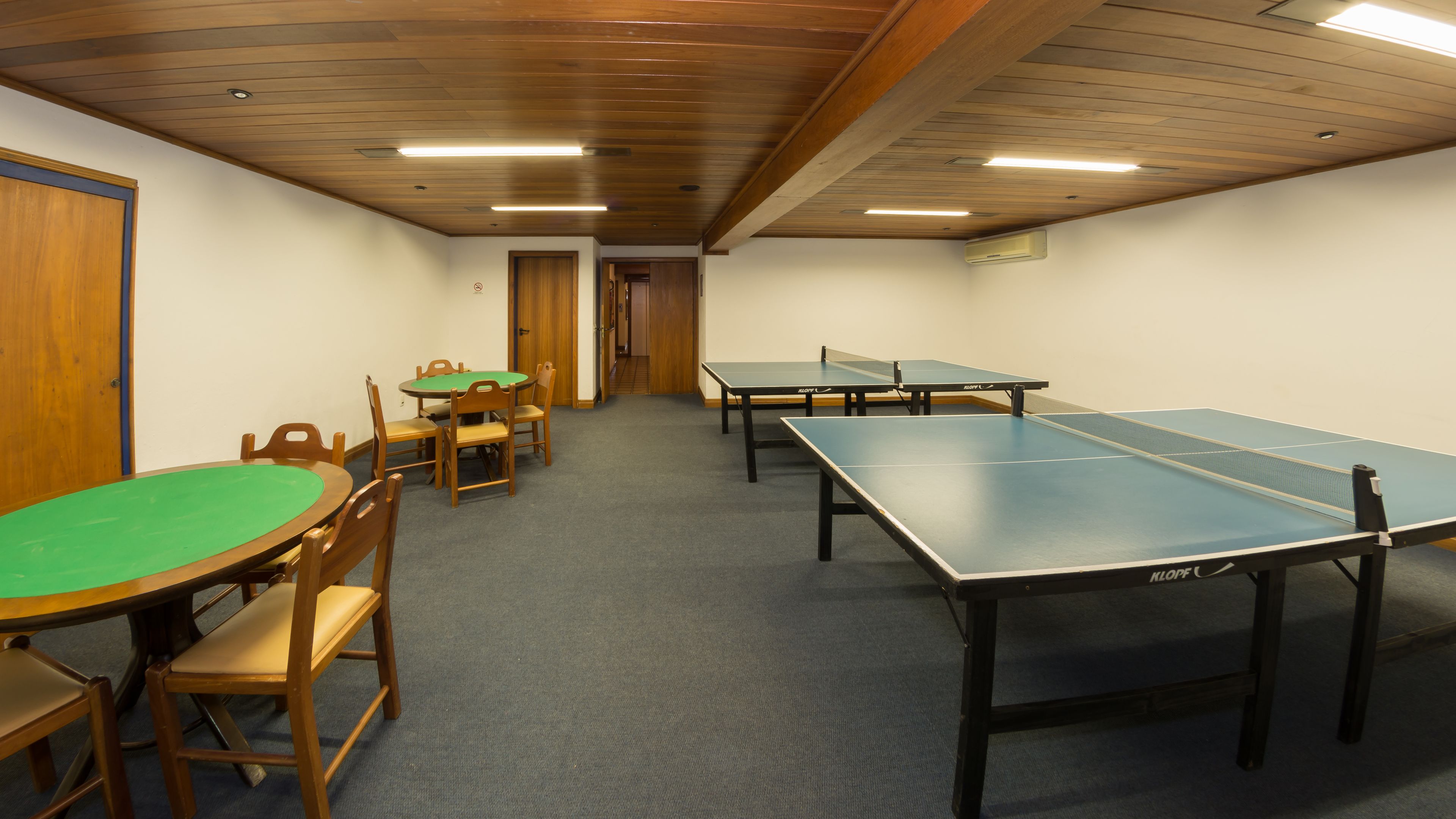 A room with ping pong tables, chairs, and a door.