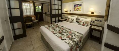 A hotel room with a large bed, a desk, a chair, and a small table.