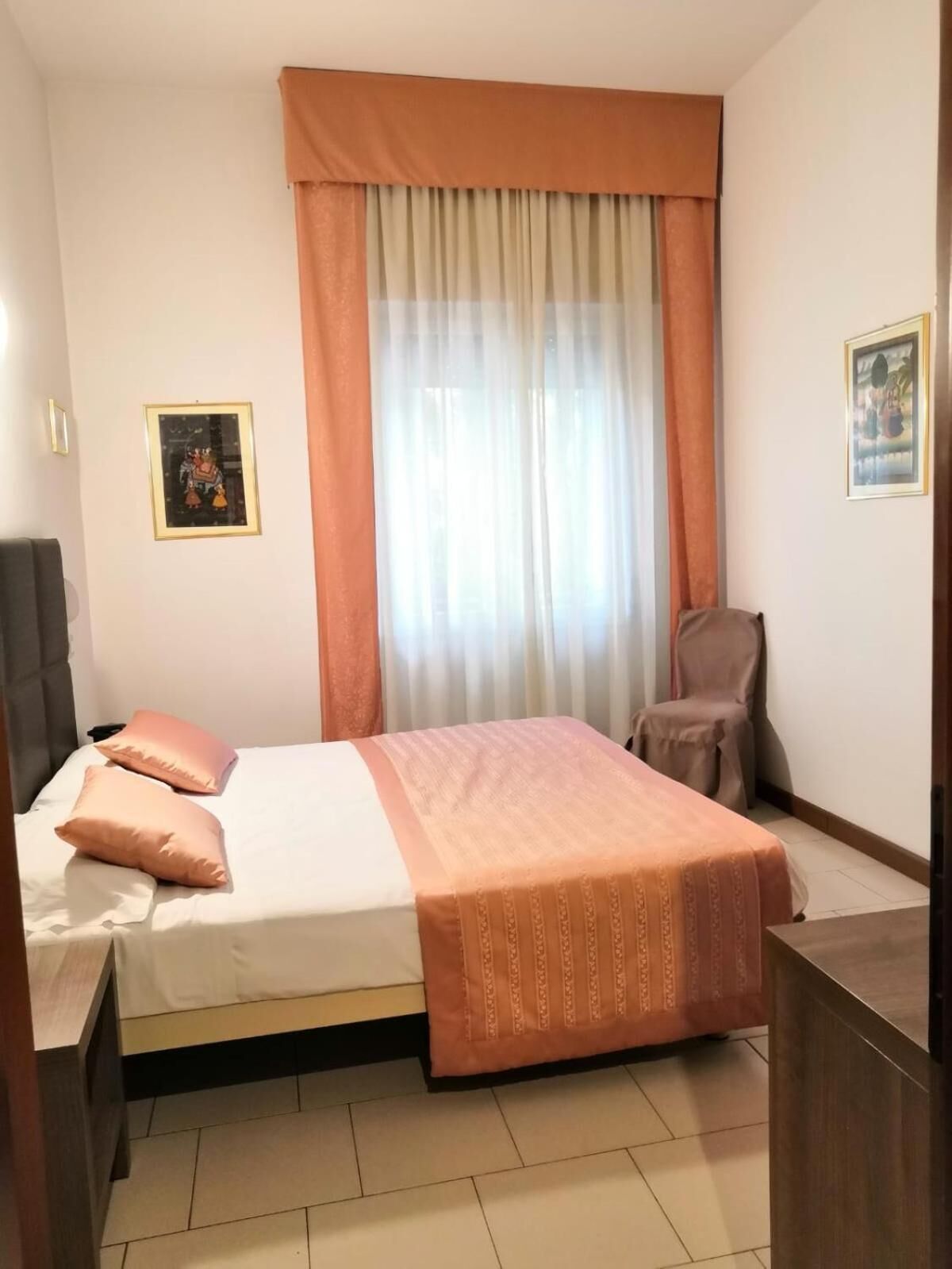 A bedroom with a bed, a chair, a desk, and curtains.
