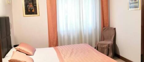 A bedroom with a bed, a chair, a desk, and curtains.