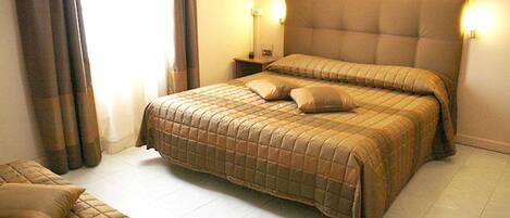 Una habitación de hotel con una cama grande, dos mesitas de noche y un pequeño sofá.