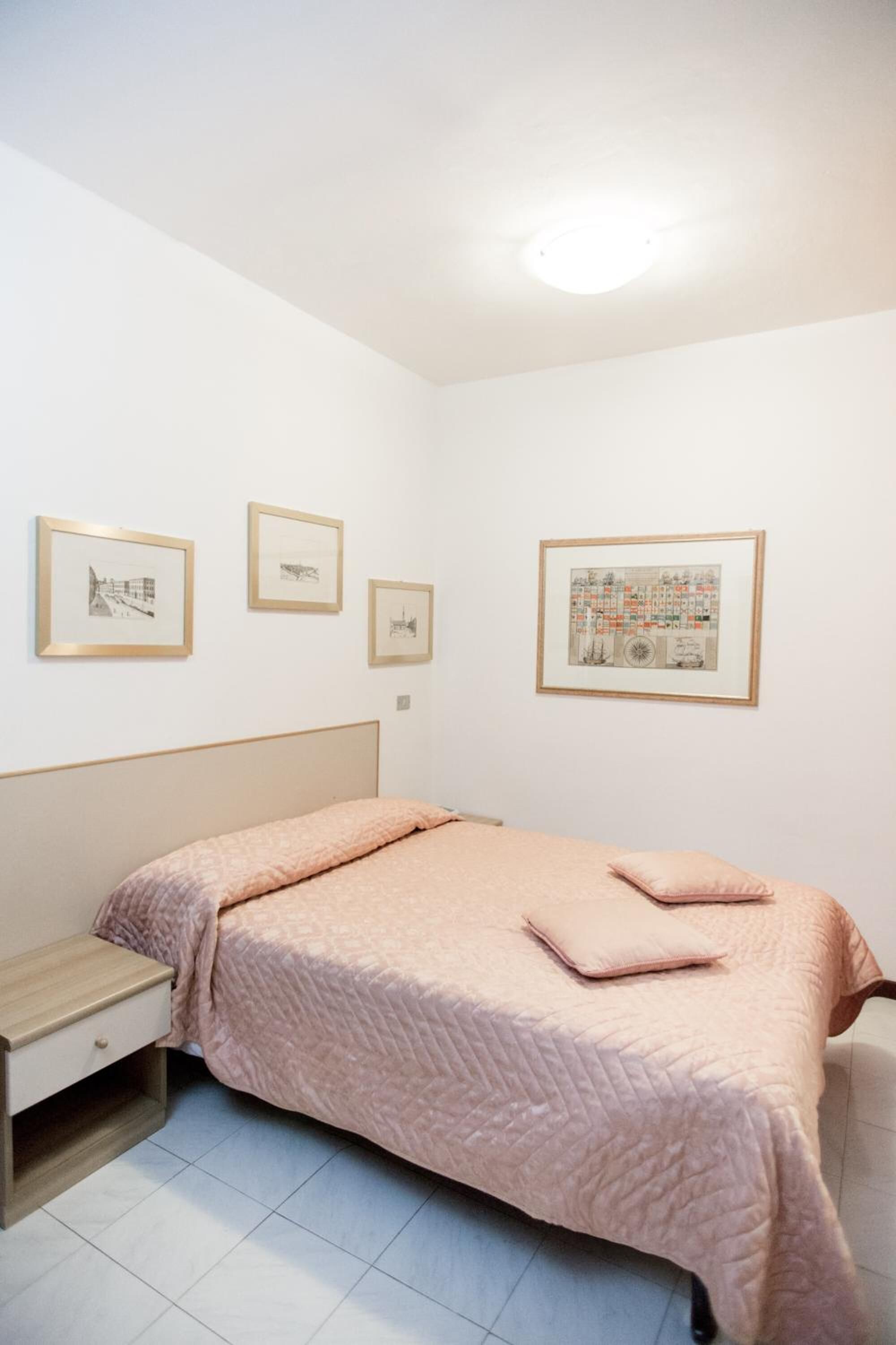 A bedroom with a bed, a nightstand, and three framed pictures on the wall.