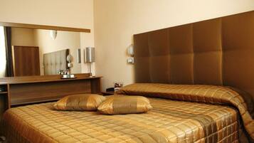 Een hotelkamer met een groot bed, een houten hoofdbord, een spiegel en een nachtkastje.